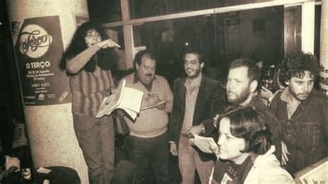 Grupo reunido em torno de uma coluna com cartaz, em foto antiga do GALF